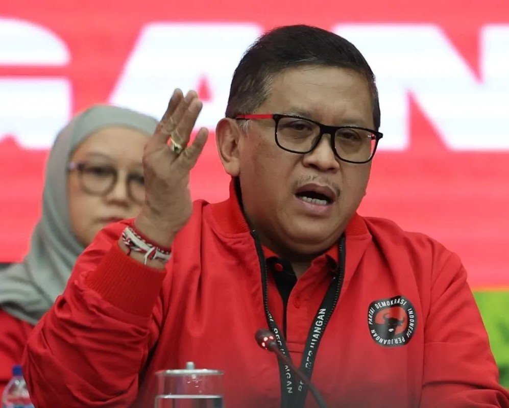 Hasto Kristiyanto dalam konferensi pers membahas dugaan kriminalisasi hukum yang menimpanya, berlatar belakang simbol PDIP