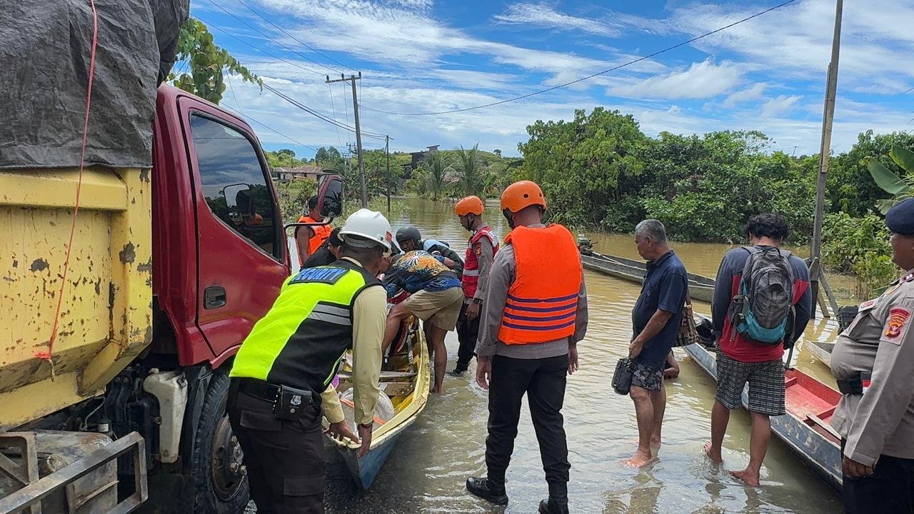 Petugas Brimob Polda Kaltim membantu warga menaiki perahu evakuasi saat banjir merendam jalanan di Kabupaten Berau, Kalimantan Timur.