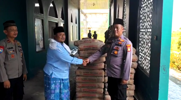 Personel Polsek Cikarang Pusat menyerahkan bantuan semen dalam kegiatan Bakti Religi Hari Bhayangkara ke-79 di Masjid Ponpes Nurul Falah, Desa Hegarmukti, Bekasi.