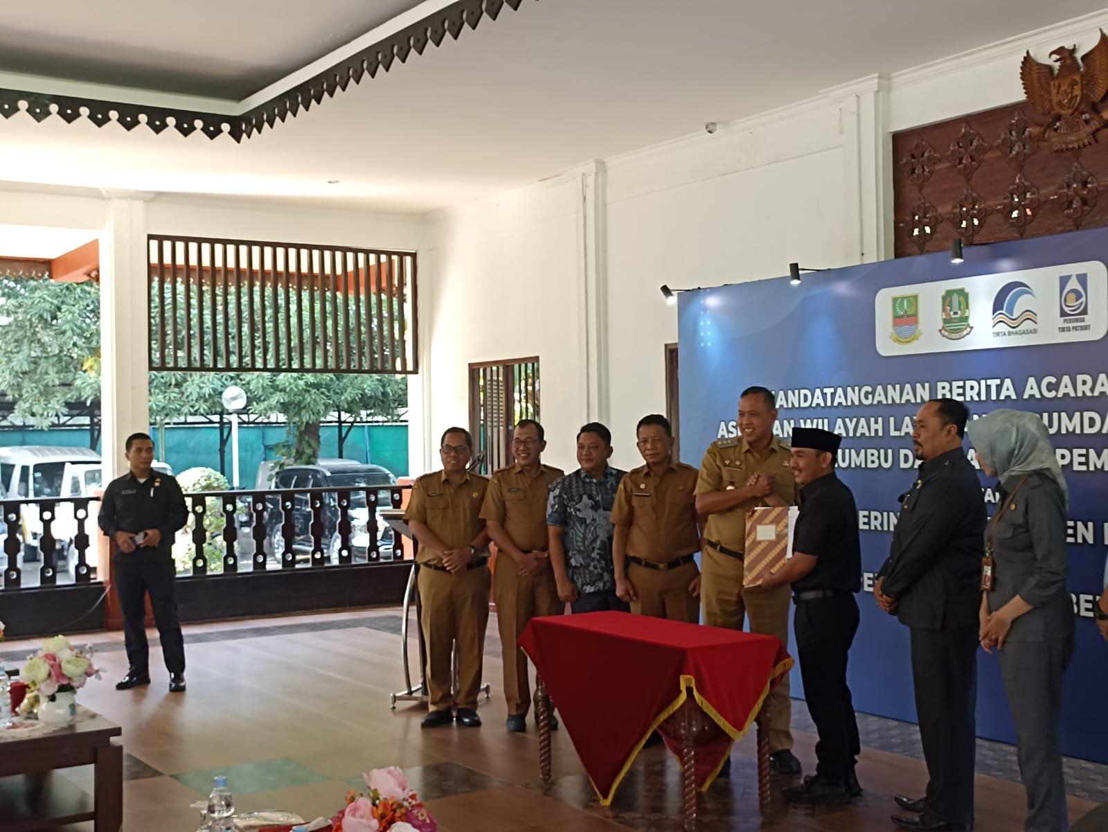 Bupati Bekasi dan Wali Kota Bekasi berjabat tangan dalam acara serah terima aset Perumda Tirta Bhagasasi di Pendopo Wali Kota Bekasi pada 22 Juli 2025.